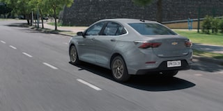 Vista trasera del Chevrolet Onix Plus conduciendo en camino urbano