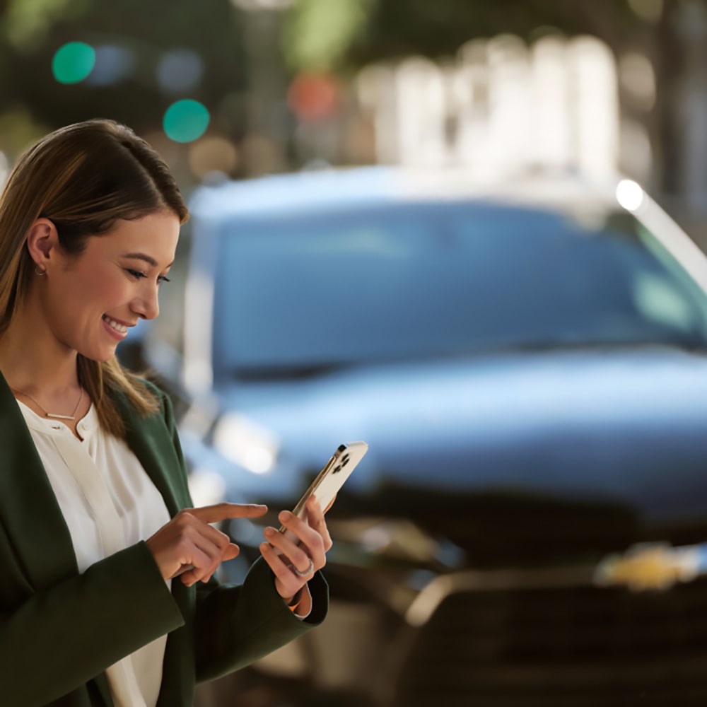 Mujer utilizando aplicación móvil para controlar su Chevrolet, tecnología inteligente que facilita tu vida