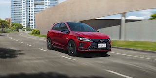 Vista frontal lateral del Onix 2026 color Rojo Jinx conduciendo en ruta urbana