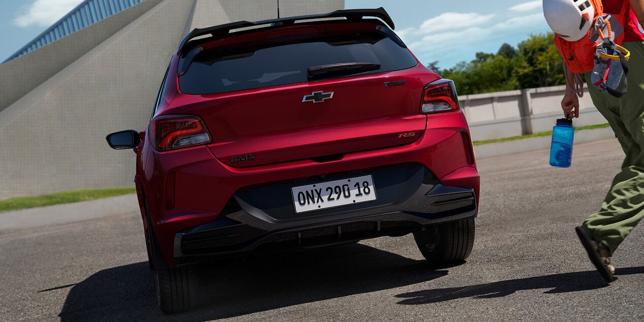 Vista trasera del Chevrolet Onix 2026 color rojo Jinx estacionado en área urbana