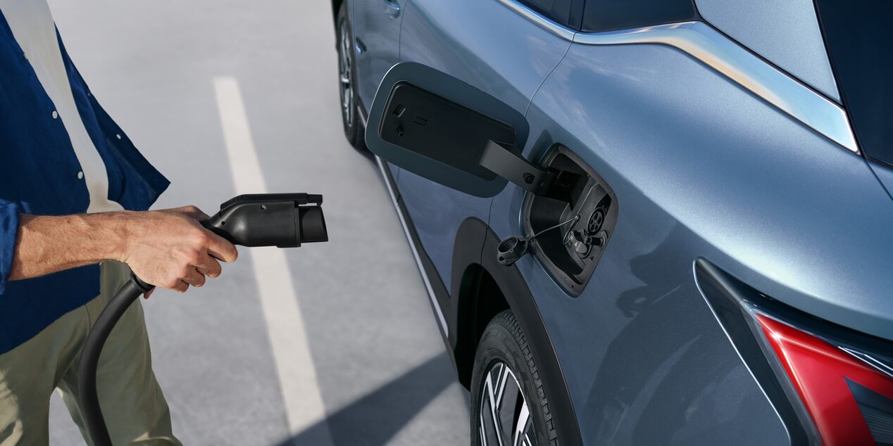 Persona conectando cargador en vehículo Chevrolet eléctrico.