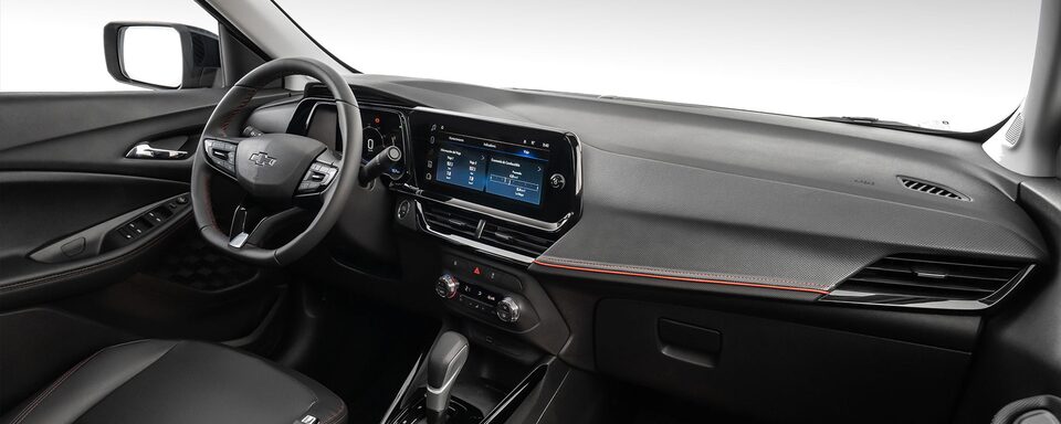 Vista interior y delantera de la Chevrolet Montana, mostrando volante, pantalla central y controles y guantera.
