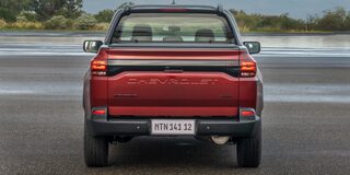 Imagen de una Chevrolet Montana estacionada en una zona descampada al aire libre vista desde atrás.