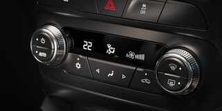 Panel de control del climatizador en el interior de una Chevrolet Montana, con perillas cromadas, pantalla digital central que marca 22 grados y botones para ajustar ventilación, temperatura y modo de circulación de aire.